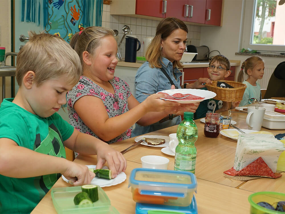 Kinder und Lehrkraft beim Essen in der Küche