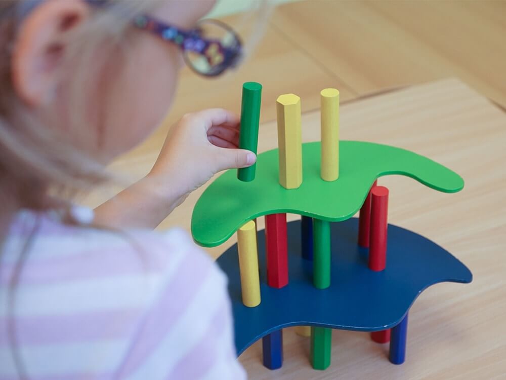 Kind baut mit Bausteinen bunten Spielzeugturm