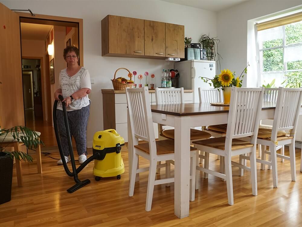 Eine Person saugt mit einem Staubsauger den Küchenboden